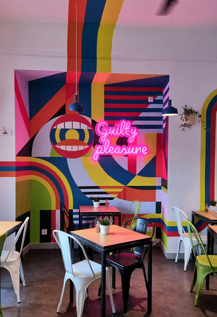 geometric mural that declares ‘Guilty Pleasure’ in glowing pink letters